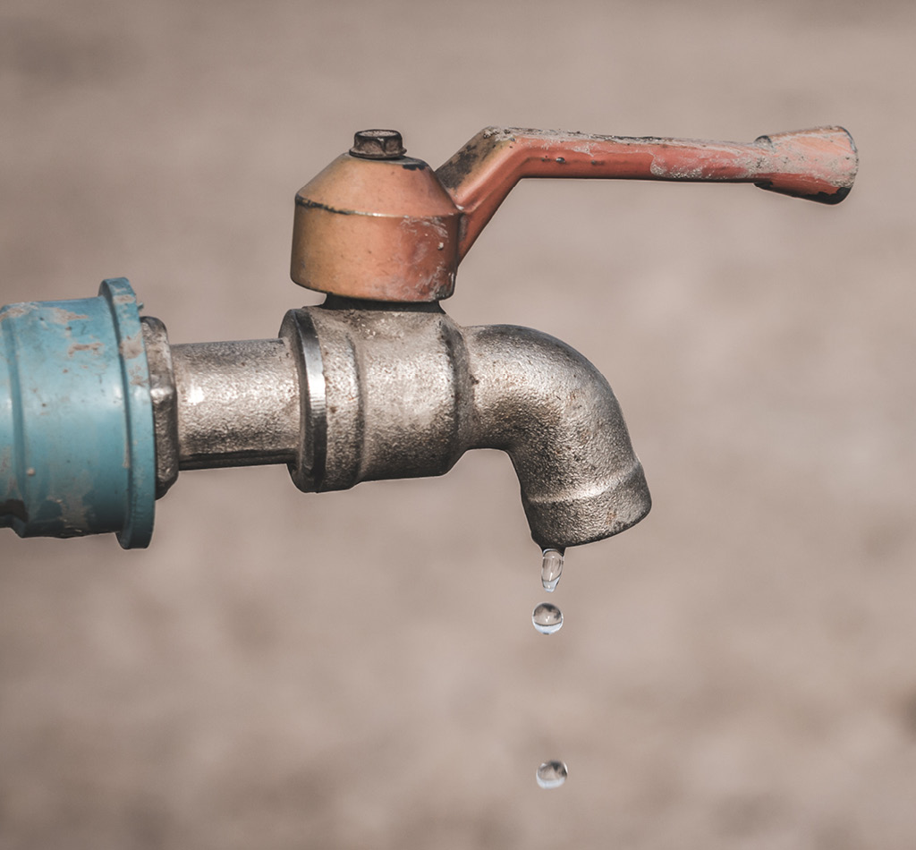 Close-up of an old water faucet leaking a few water drops.