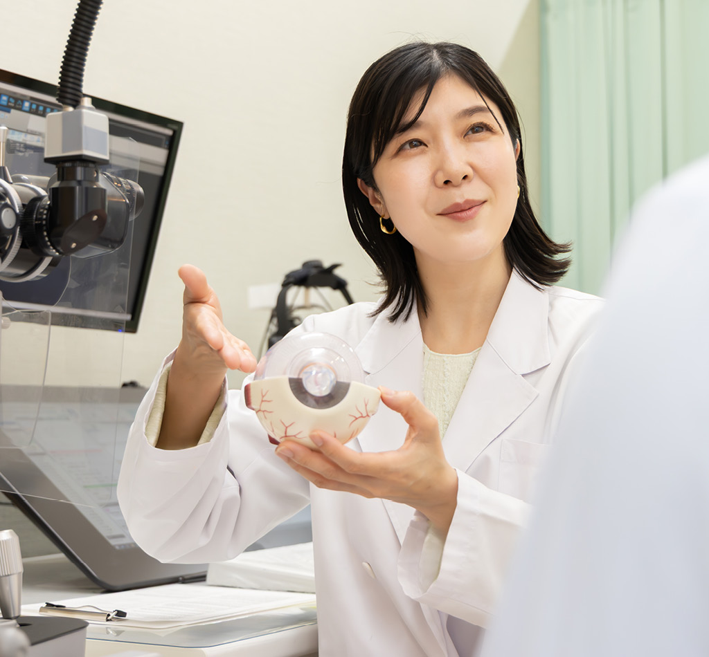 An ophthalmologist explains the examination while holding an eyeball model.